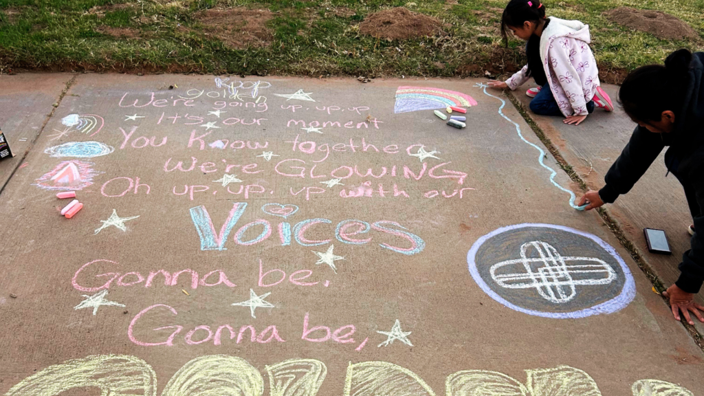 Students and families write encouraging messages to teachers and other students for Chalk the Walk during Love Our Schools Week
